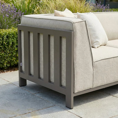 Beige outdoor sofa with grey metal frame and textured cushions on a patio