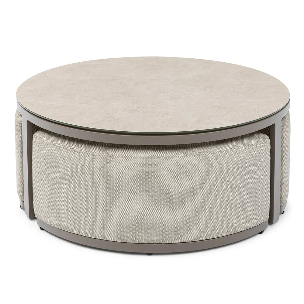 Round coffee table with light stone top and fabric upholstered base in neutral tones