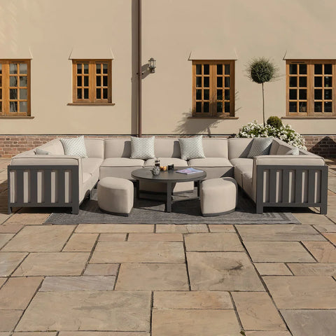Outdoor corner sofa set with grey cushions, round coffee table, and stools on patio
