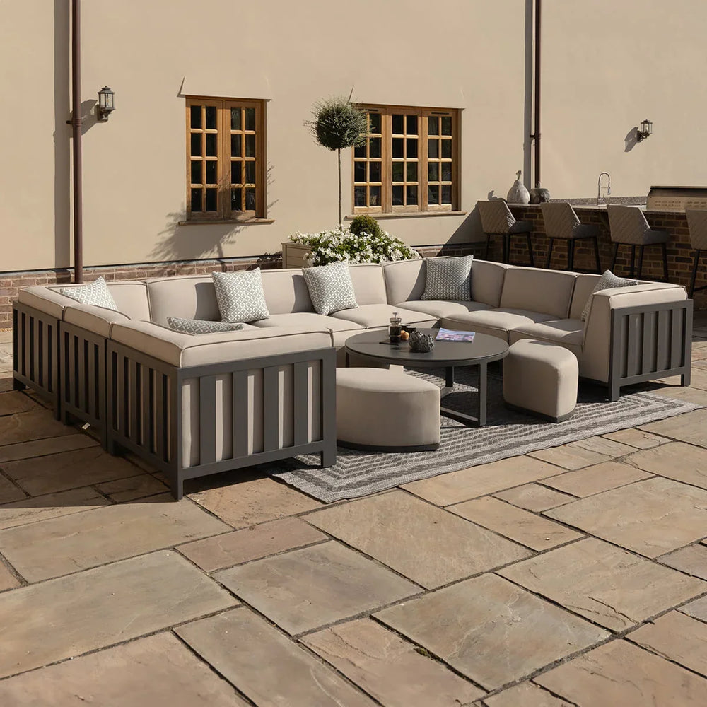 Outdoor corner sofa set with grey frame, beige cushions, round coffee table and stools on patio