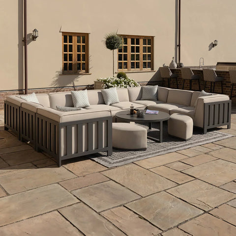 Outdoor corner sofa set with grey frame, beige cushions, round coffee table and stools on patio