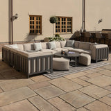 Outdoor corner sofa set with grey frame, beige cushions, round coffee table and stools on patio