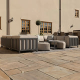Grey outdoor corner sofa set with cushions and ottomans on stone patio