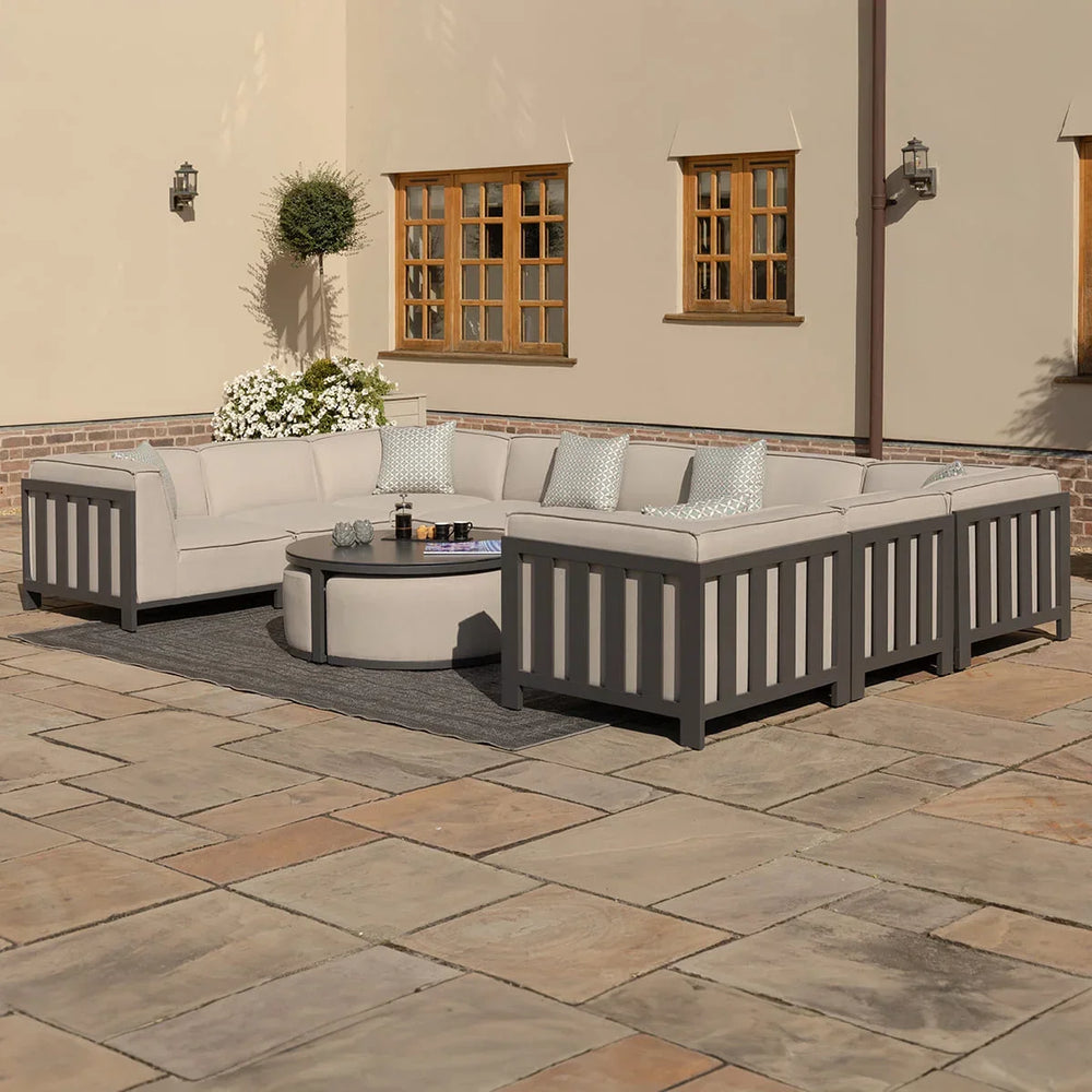 Grey outdoor corner sofa set with cushions and round coffee table on patio