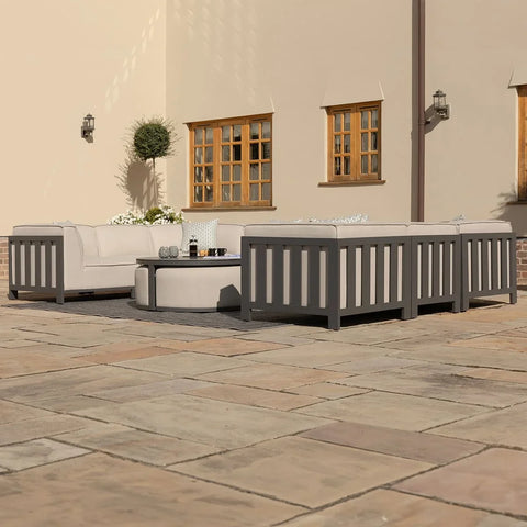 Grey outdoor sofa set with cream cushions and round coffee table on a stone patio