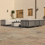 Grey outdoor sofa set with cream cushions and round coffee table on a stone patio