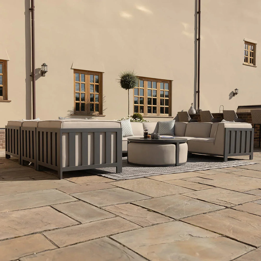 Grey outdoor sofa set with cushions and round coffee table on stone patio