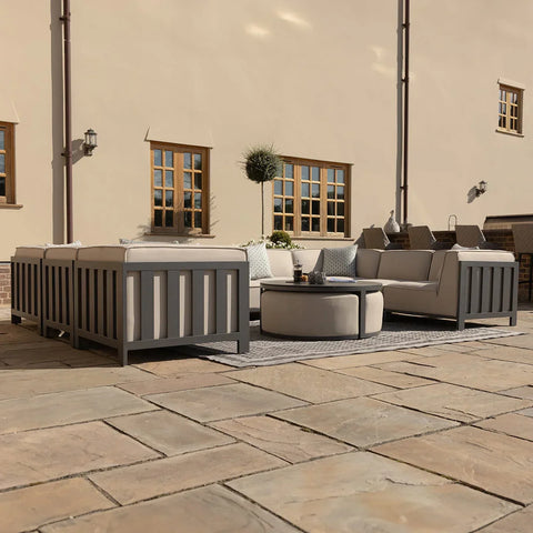Grey outdoor sofa set with cushions and round coffee table on stone patio