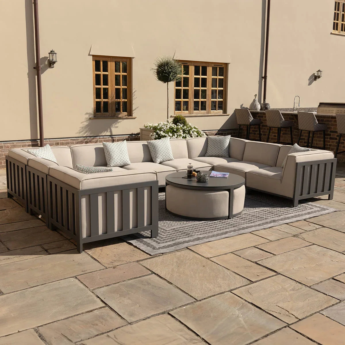 Beige outdoor corner sofa set with grey frame and round coffee table on patio