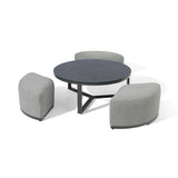 Round coffee table with black top and three curved grey fabric stools grouped around