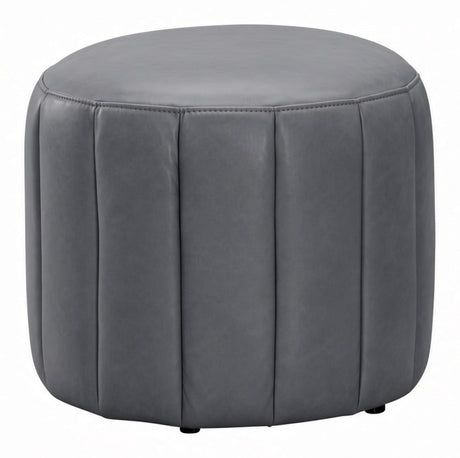 A round gray upholstered ottoman with vertical channel tufting and small black feet, shown on a plain white background.