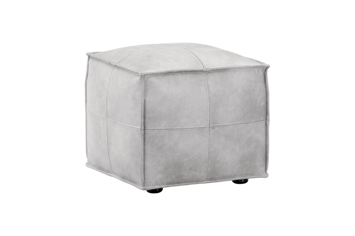 A square ottoman with a light gray faux leather or suede-like finish, featuring stitched panel details and small black feet, shown on a plain white background.