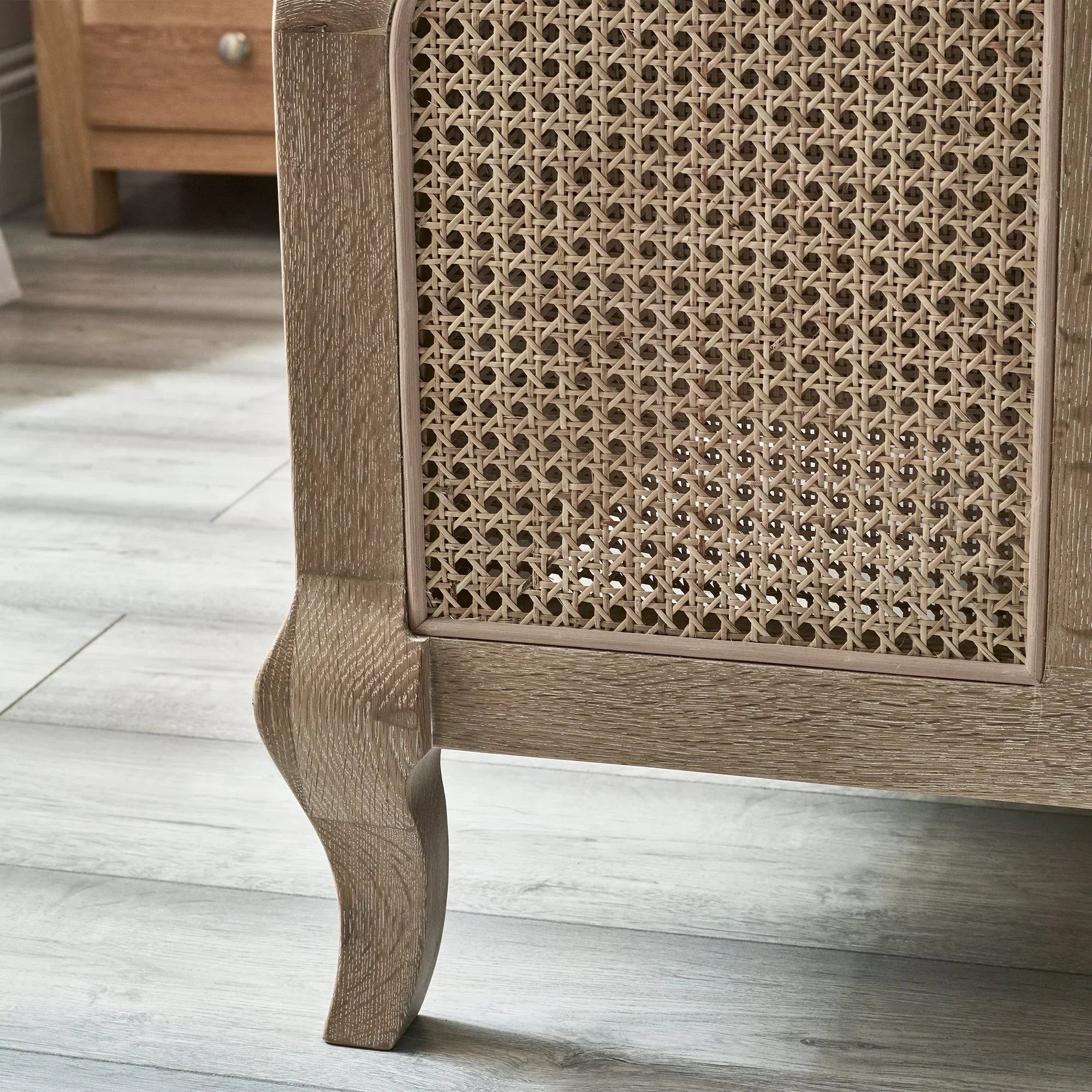 Oak side table with woven cane panel and curved leg on wood floor