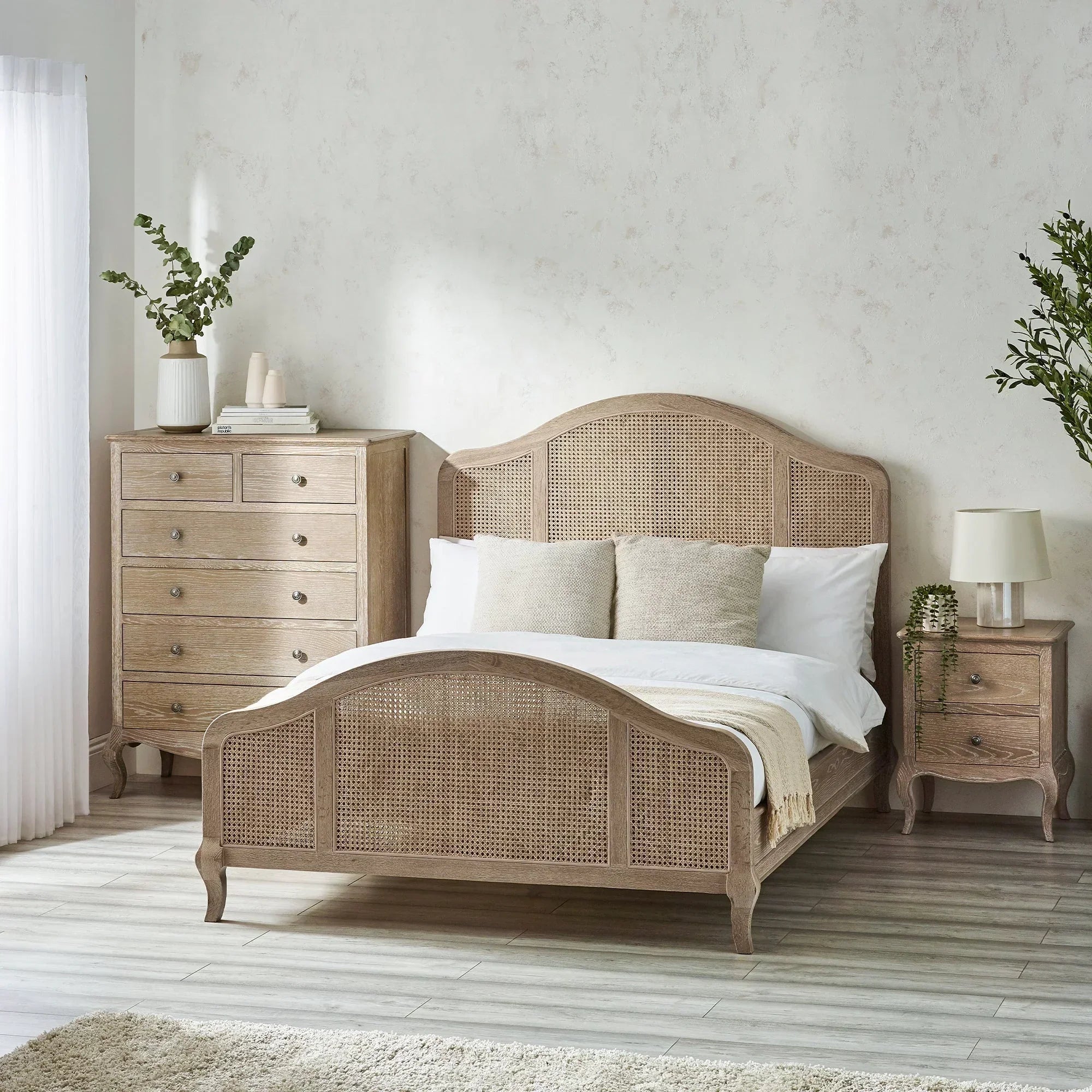 King size rattan bed with neutral bedding and matching wooden drawers in modern bedroom