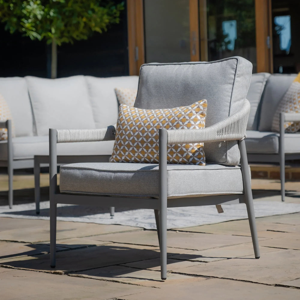 Grey garden lounge chair with cushions and a patterned scatter pillow on patio