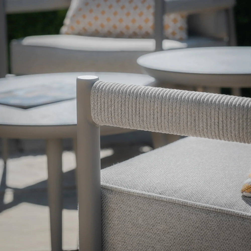 Light grey outdoor sofa with rope arm detail and matching round coffee tables