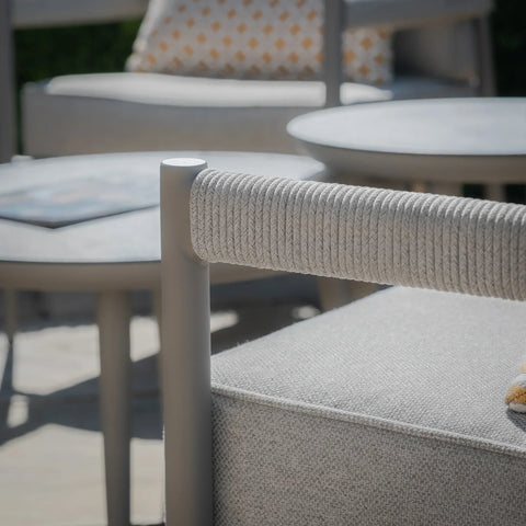 Light grey outdoor sofa with rope arm detail and matching round coffee tables