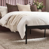 Close-up angled view of pillows and vertical spindle headboard with dark and light beige pillows and white bedding