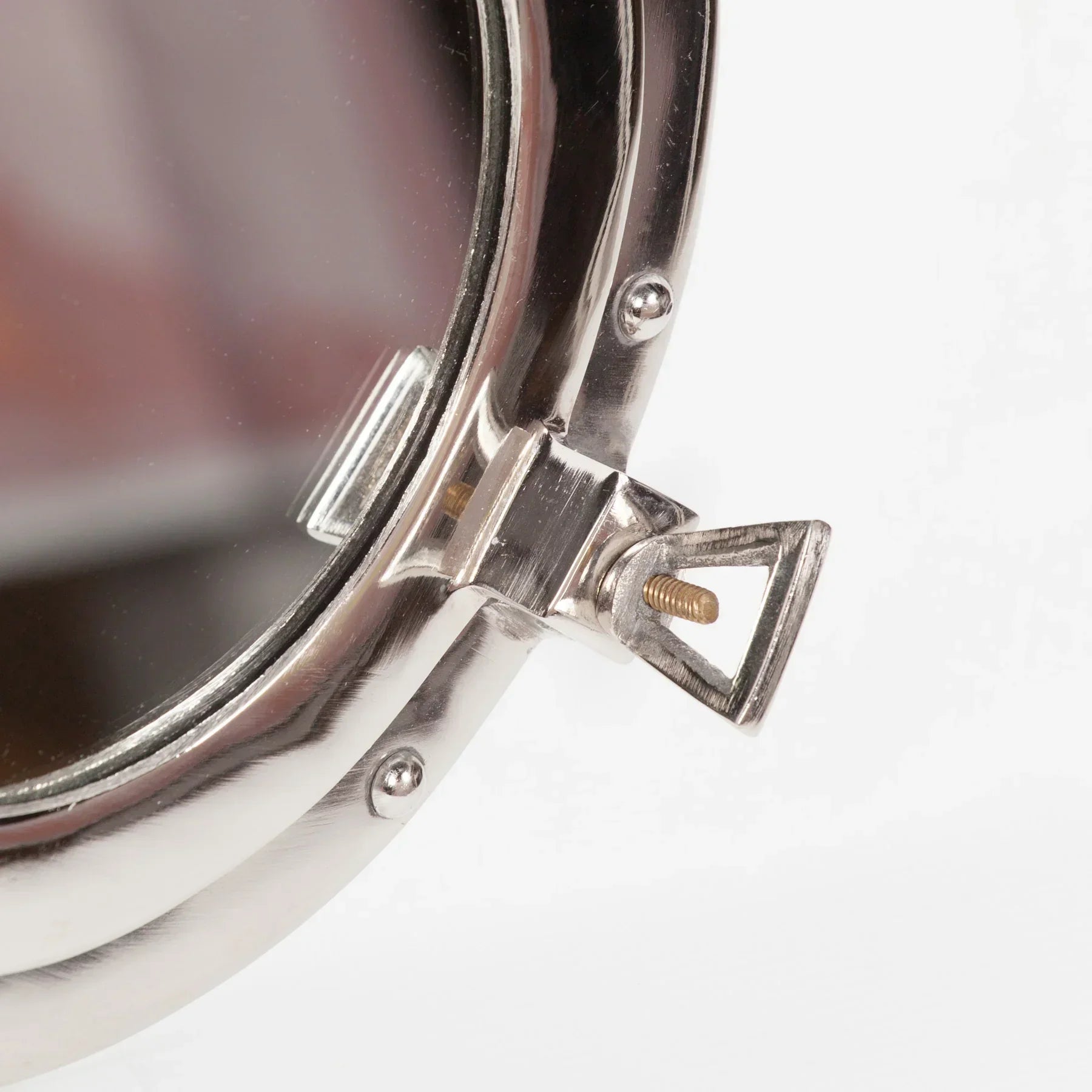Close-up of round metal mirror frame with adjustable screw and polished chrome finish