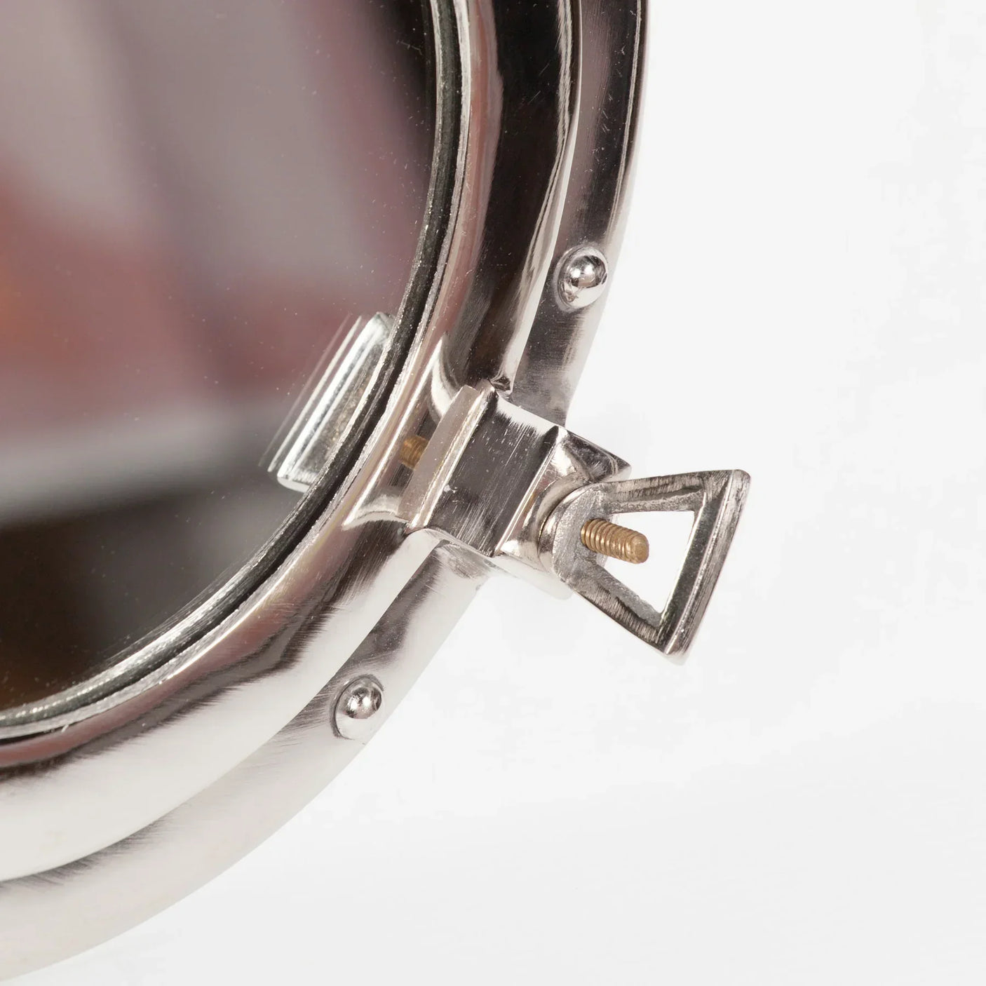 Close-up of round metal mirror frame with adjustable screw and polished chrome finish