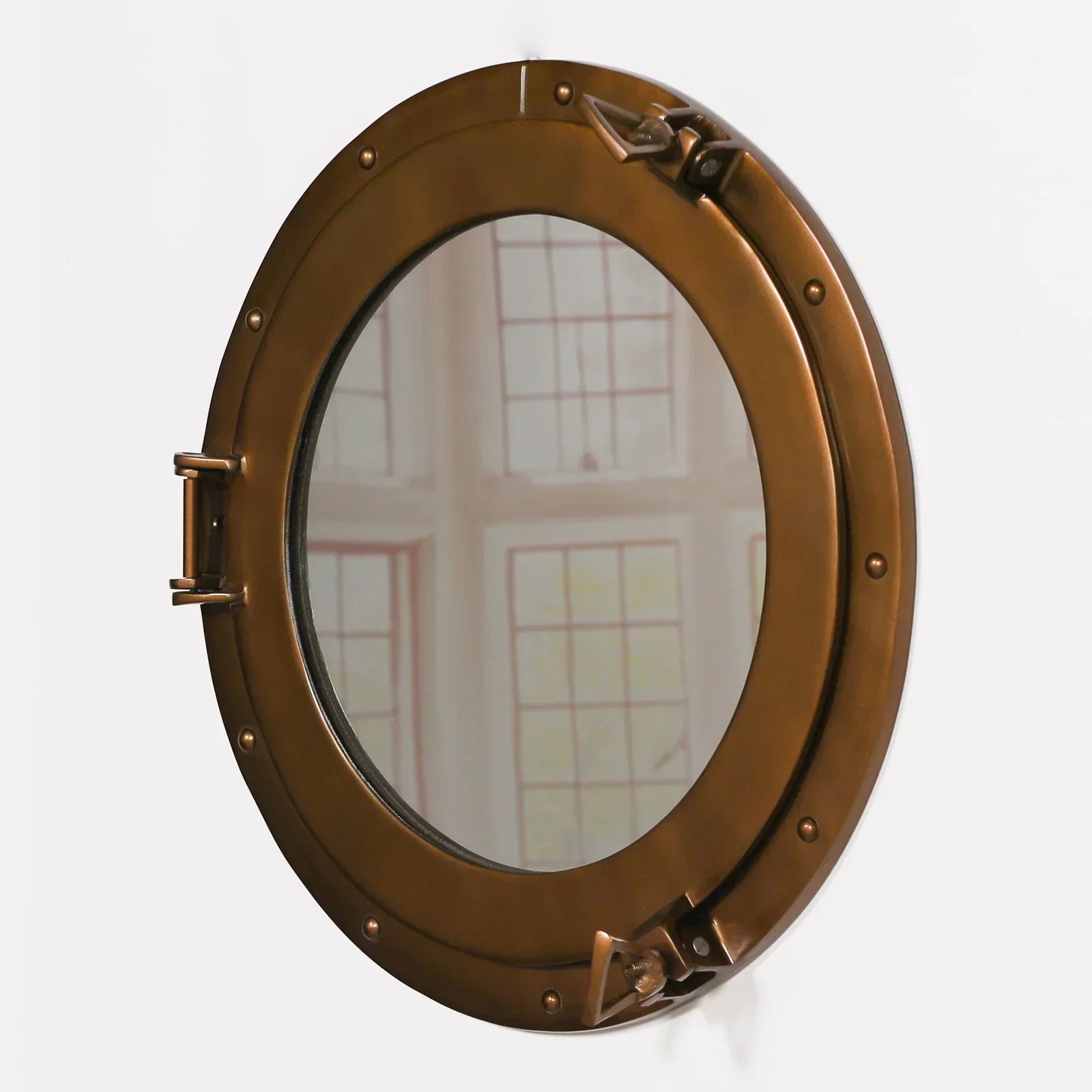 Round bronze porthole mirror with metal frame and latch detail on white wall