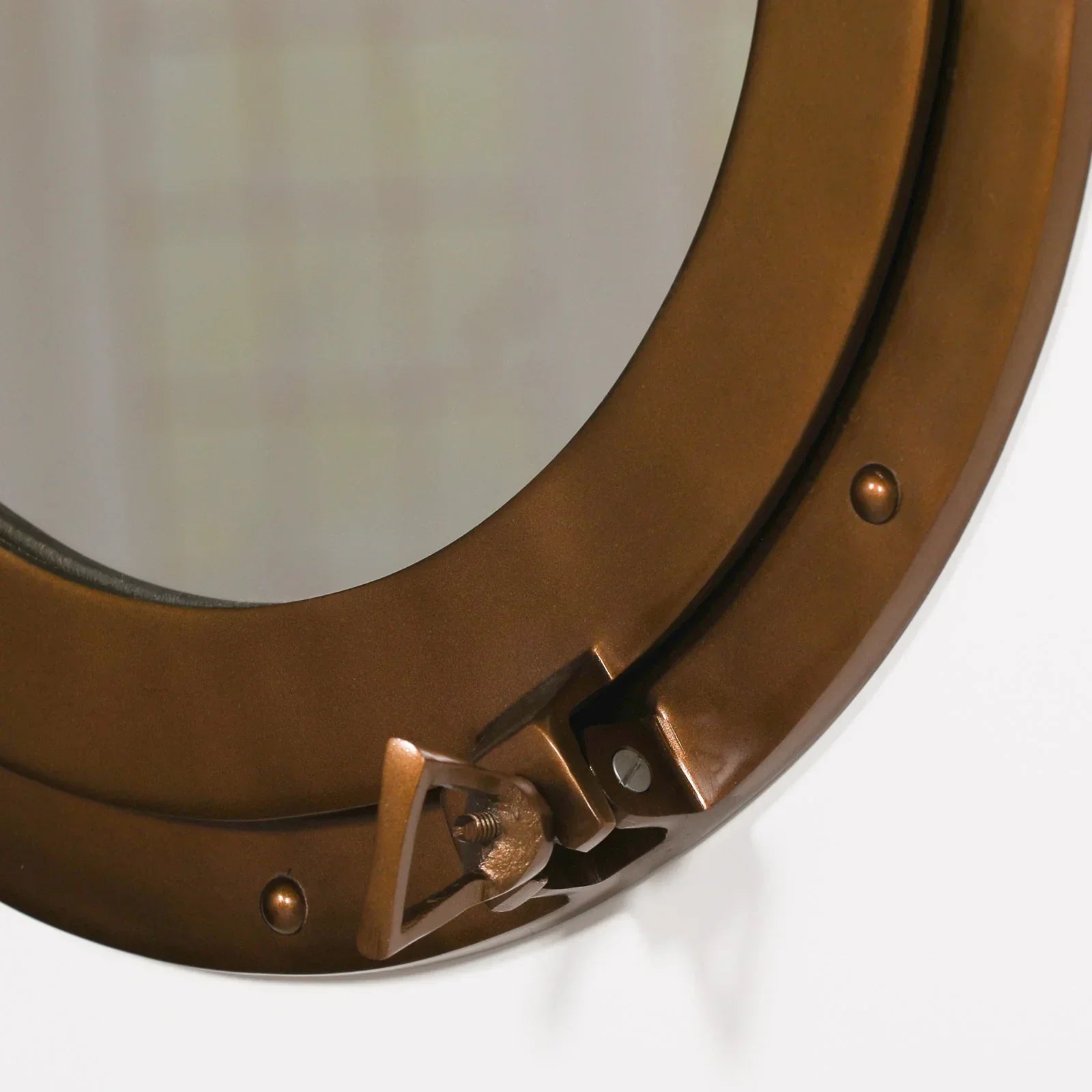 Bronze round porthole mirror with visible clasp and rivet details close-up