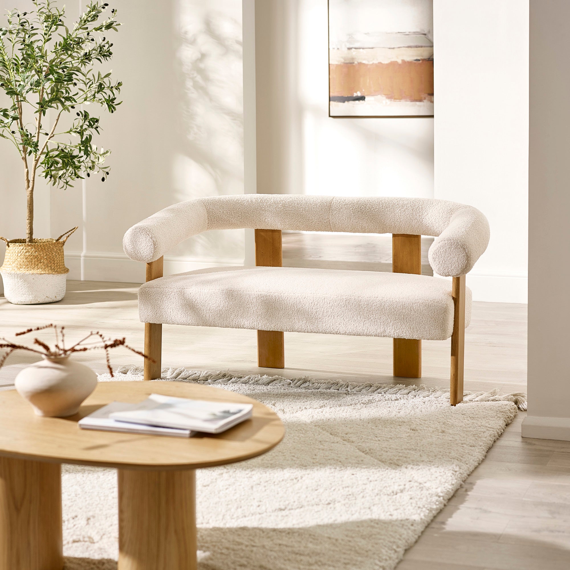 Cream boucle fabric 2 seater sofa with rounded backrest and light wood frame in bright living room