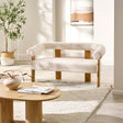 Cream boucle fabric 2 seater sofa with rounded backrest and light wood frame in bright living room