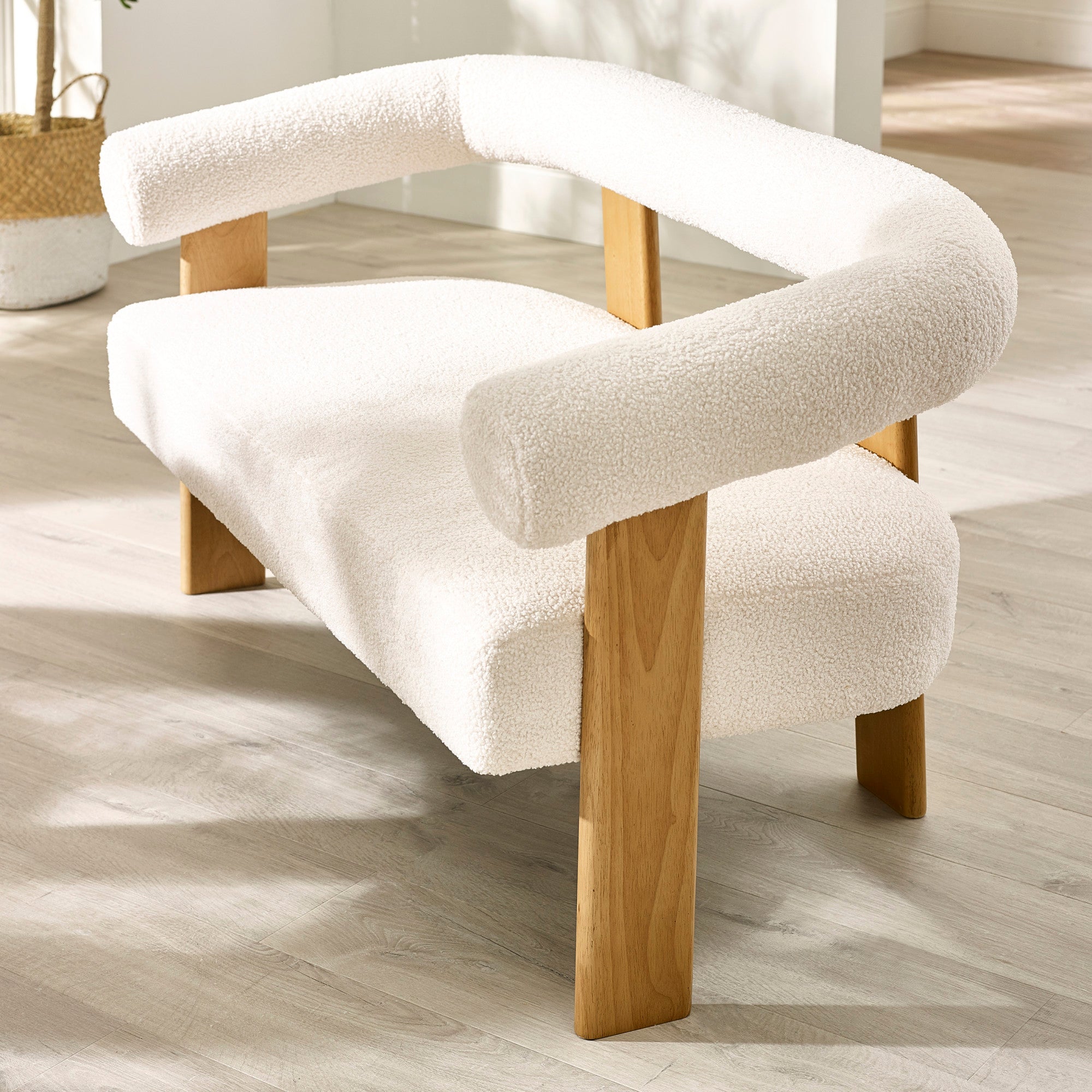 Close-up angled shot of cream boucle 2 seater sofa showing armrest, curved backrest and light wood frame