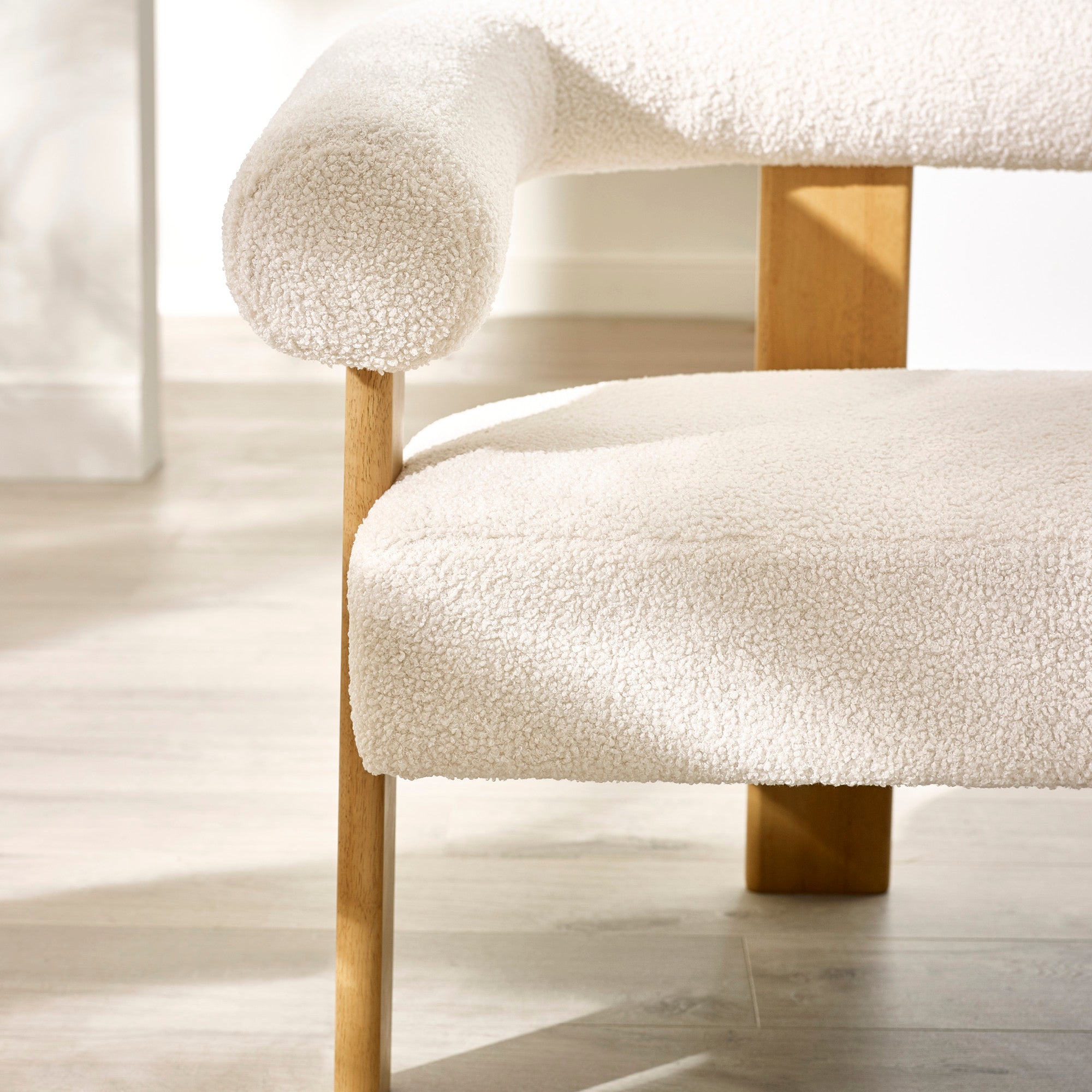 Close-up detail of cream boucle fabric seat and tubular curved backrest supported by wooden frame