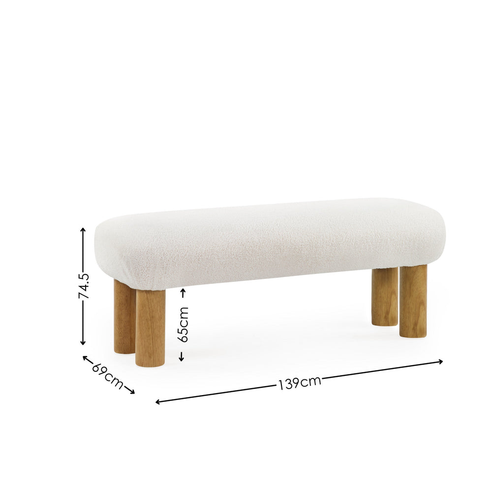 Low bench with cream textured upholstery and four rounded natural wooden legs with dimension markings on white background