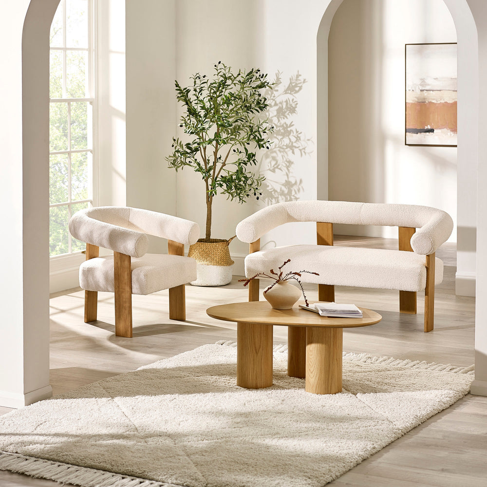 Living room with a cream boucle upholstered low bench matching armchair, wooden coffee table, indoor plant, and neutral decor