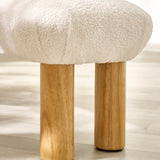 Close-up detail of light wood cylindrical legs and textured cream fabric upholstery of bench.