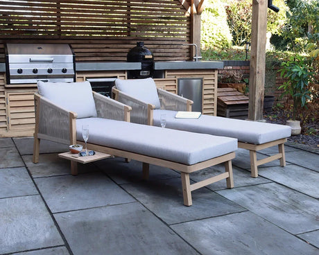 Set of two grey cushioned sun loungers with wooden frames on patio beside outdoor kitchen