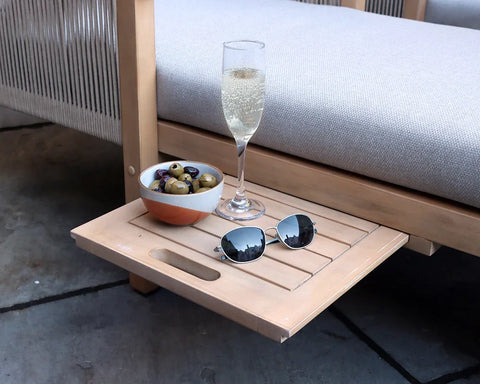 Outdoor sofa with wooden side table, bowl of olives, sunglasses, and glass of sparkling drink