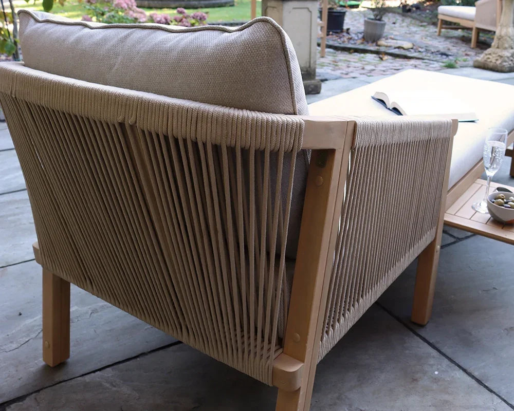 Beige rope outdoor sofa with wooden frame and cushion on patio next to side table