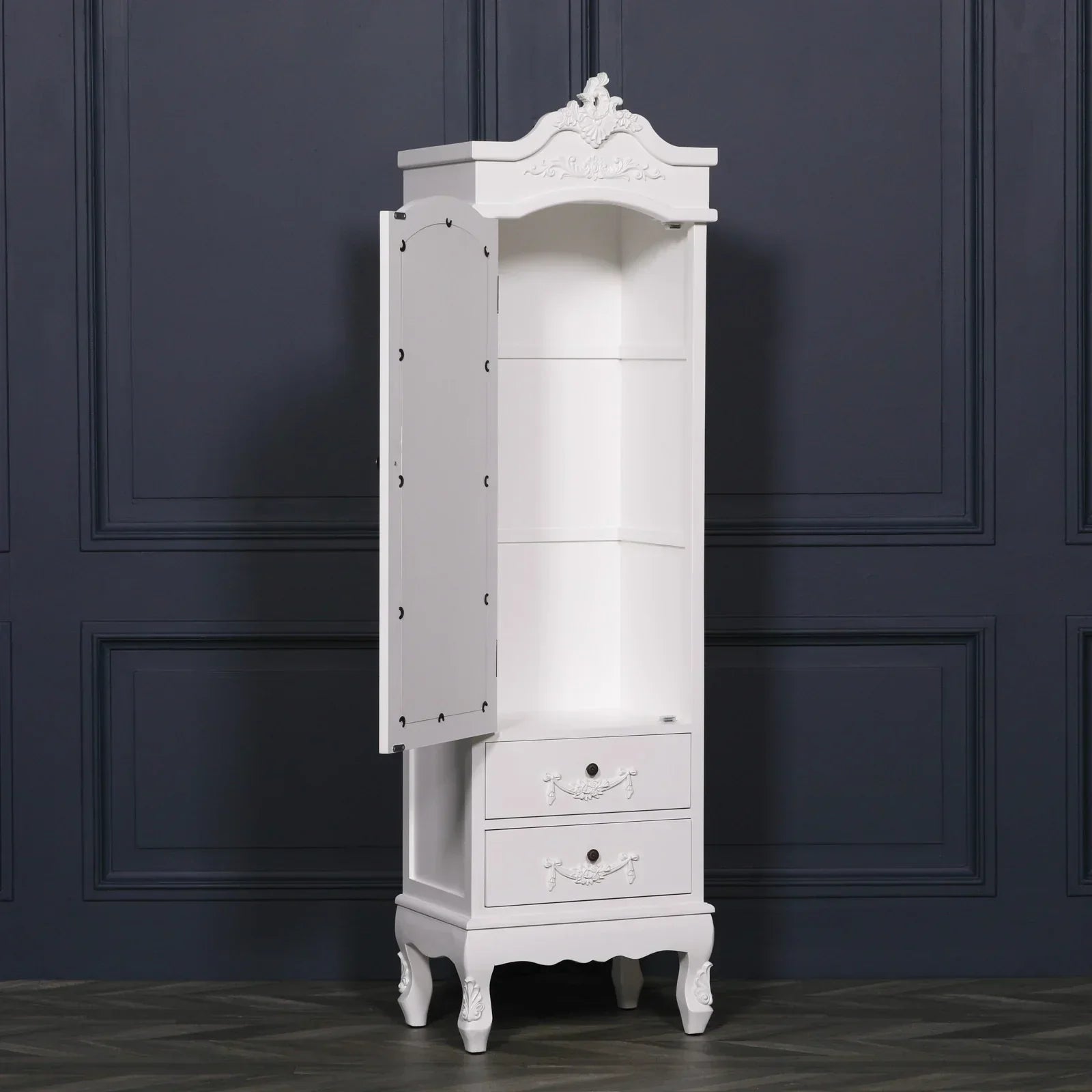 White narrow storage cabinet with open door, shelves and two drawers, against dark wall