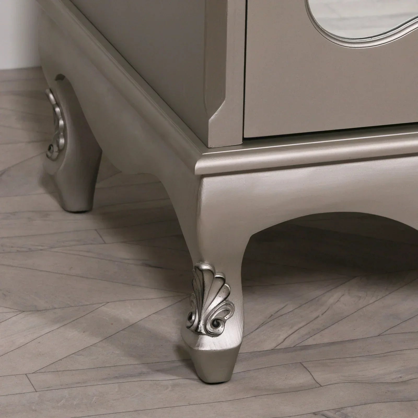 Silver chest of drawers corner with ornate carved legs on wood floor