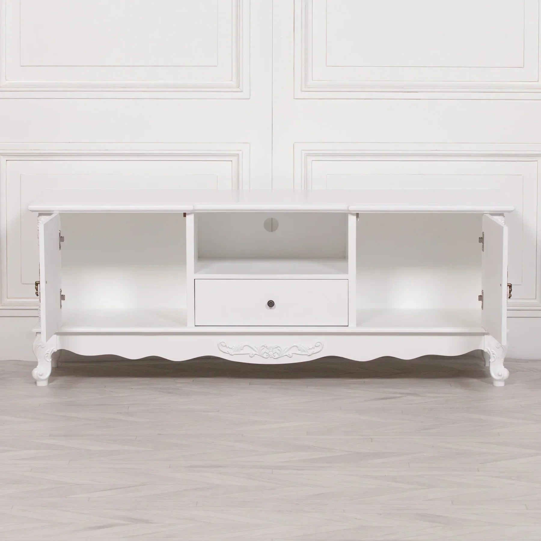 White wood TV unit with two open doors, central drawer and scalloped legs on light floor