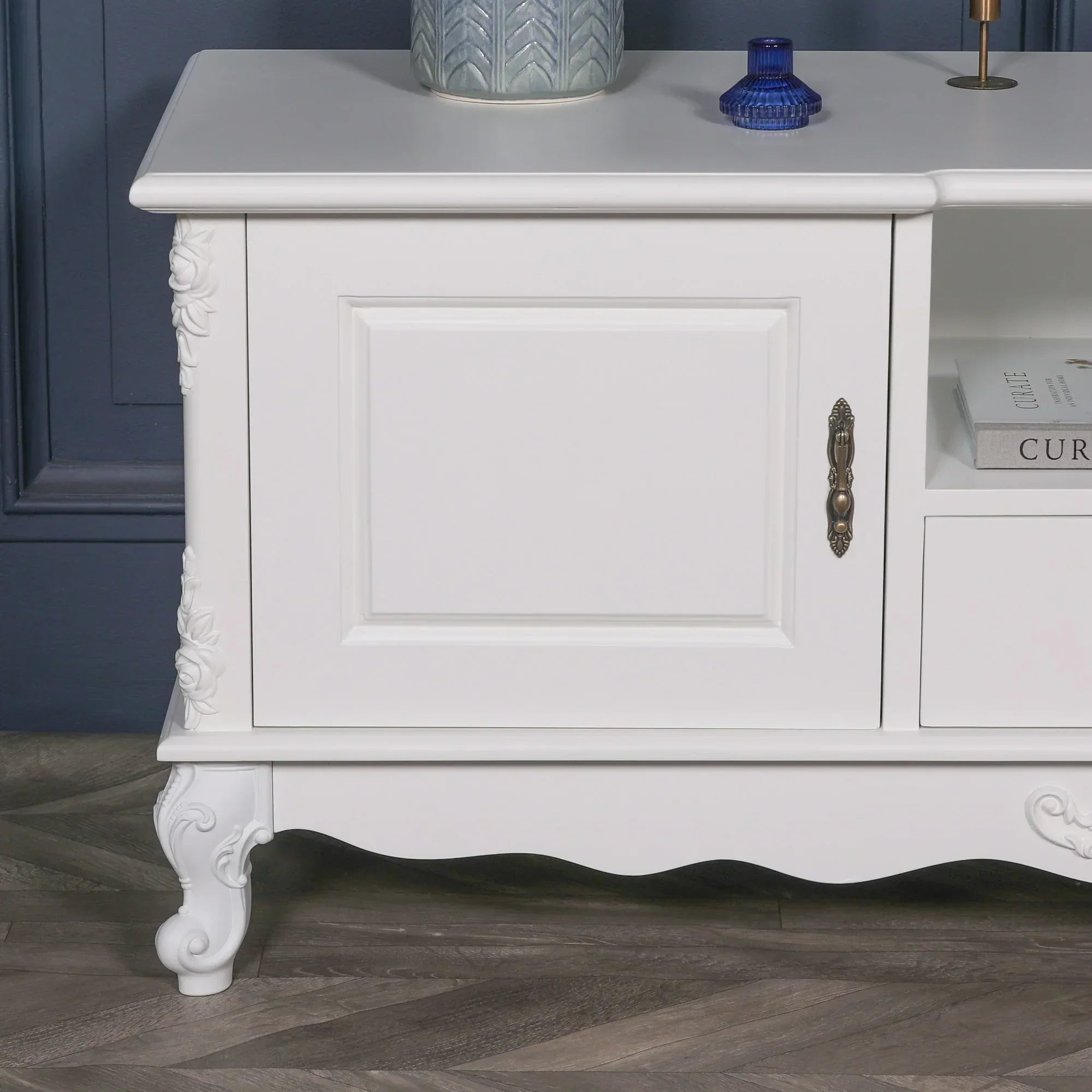 White wood TV unit with ornate carved details and brass handle, close-up front view