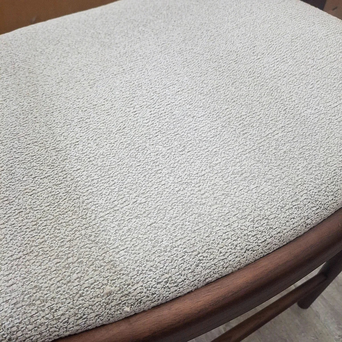 Fern barstool closeup showing light textured fabric seat with curved wooden edge