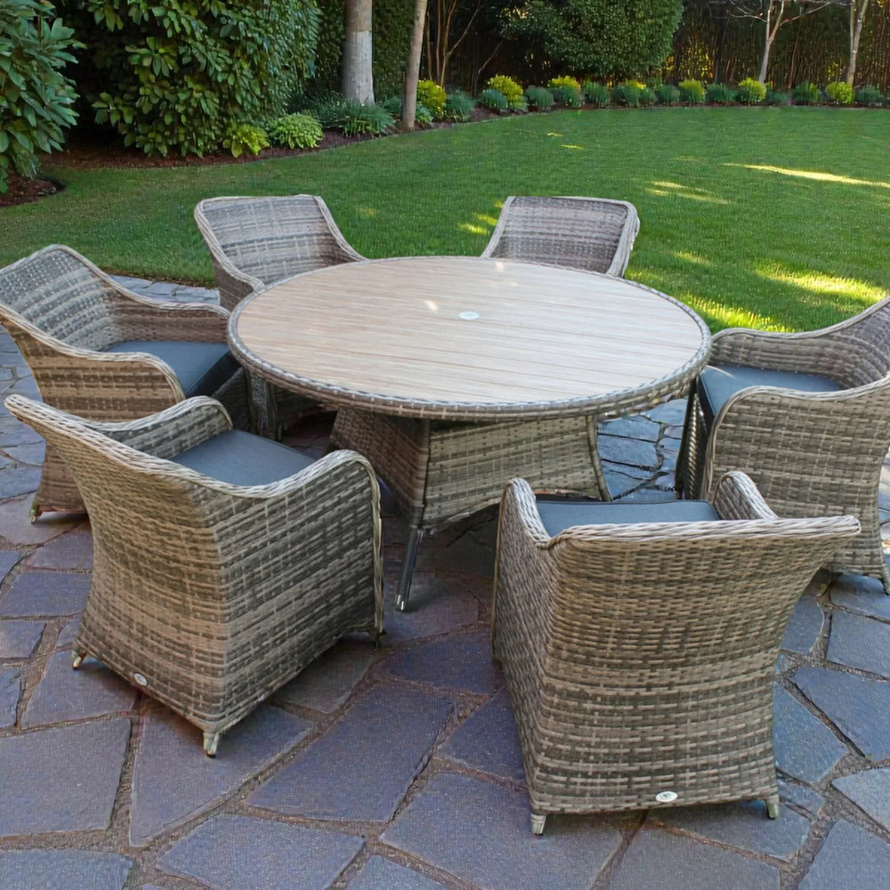 Rattan garden dining set with round wooden table and six cushioned chairs on stone patio