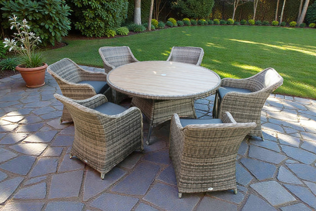 Rattan garden dining set with round wooden table and six cushioned chairs on stone patio