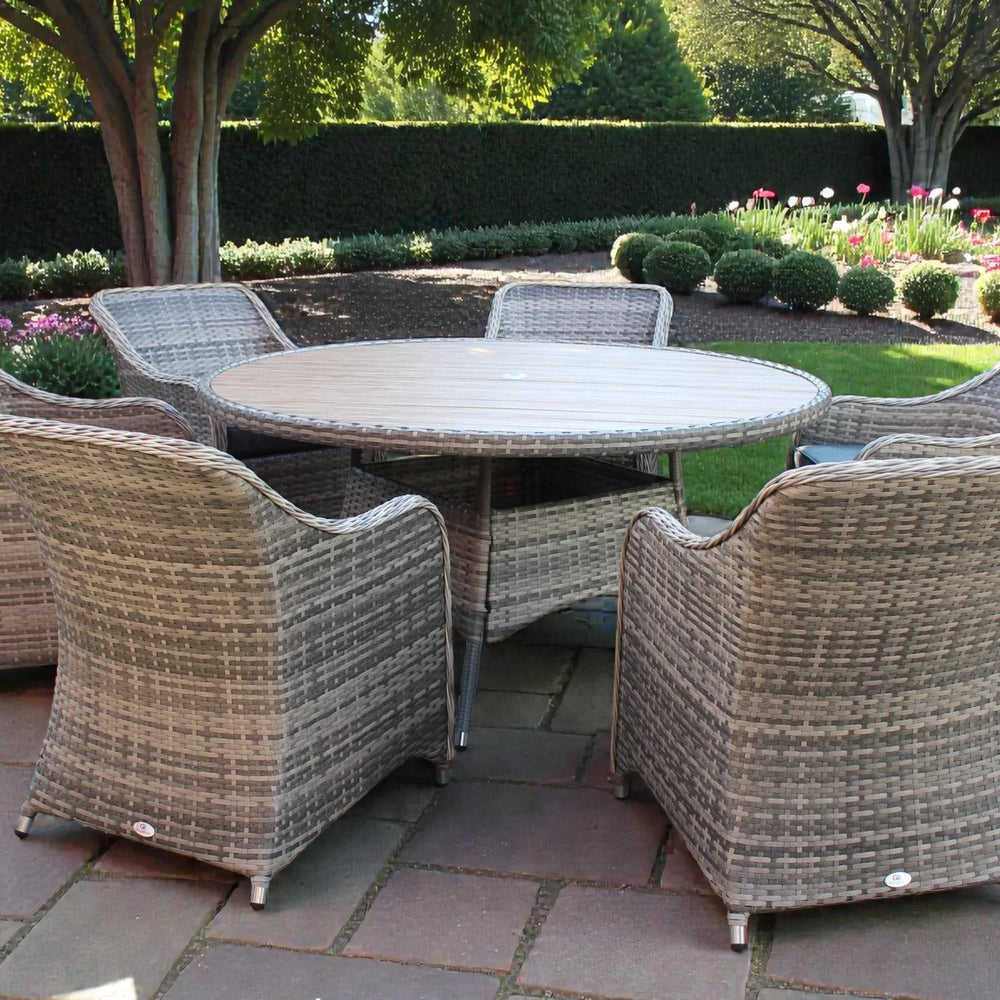 Rattan garden furniture set with round dining table and six chairs on stone patio
