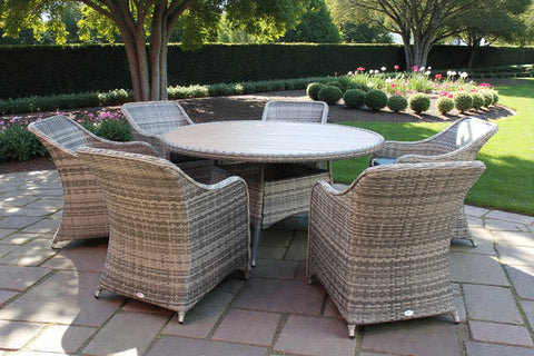 Rattan garden furniture set with round dining table and six chairs on stone patio