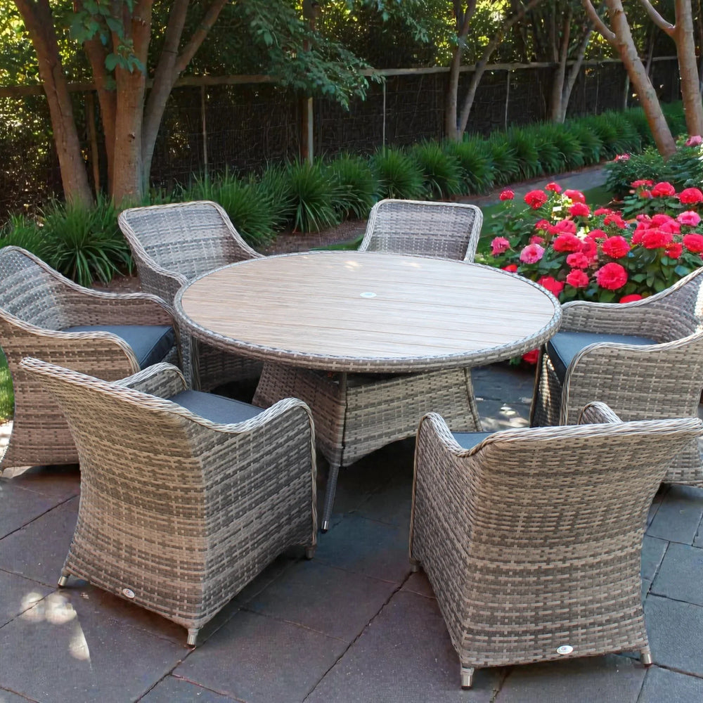 Rattan garden dining set with six cushioned chairs and round table on stone patio