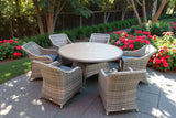 Rattan garden dining set with six cushioned chairs and round table on stone patio