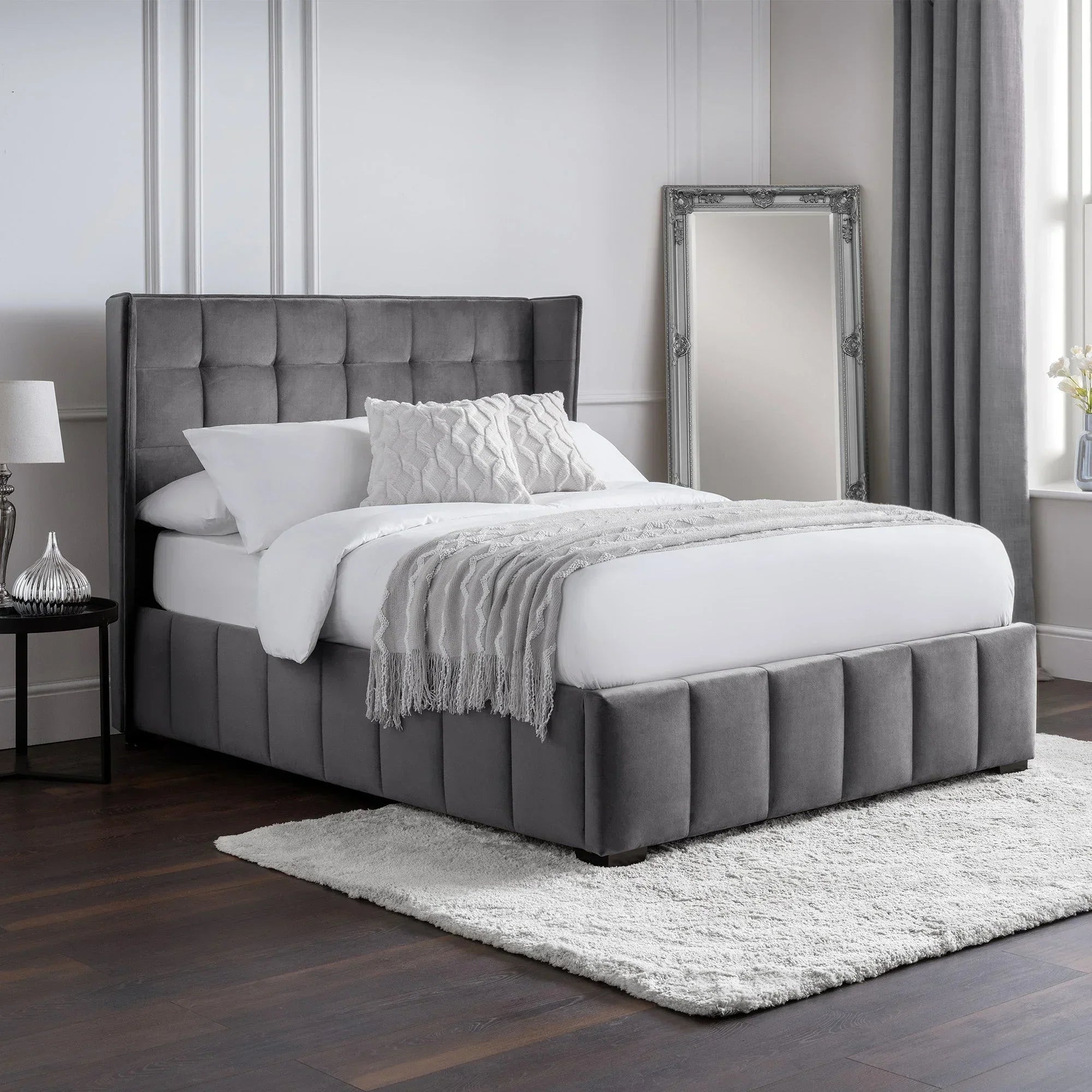 Grey upholstered bed with paneled headboard, white bedding, and decorative pillows in modern bedroom