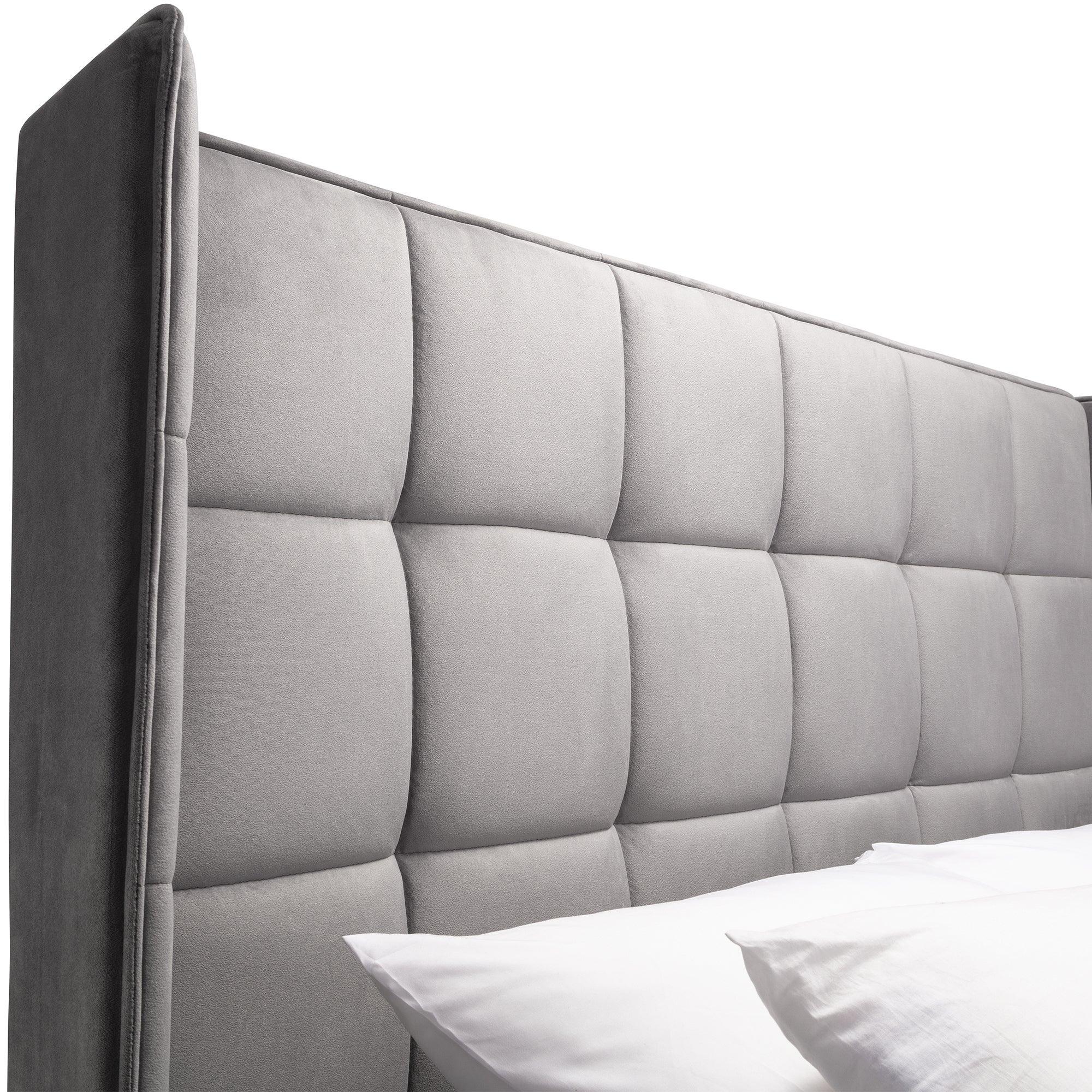 Side angle of grey ottoman bed with upholstered panel headboard and white pillows