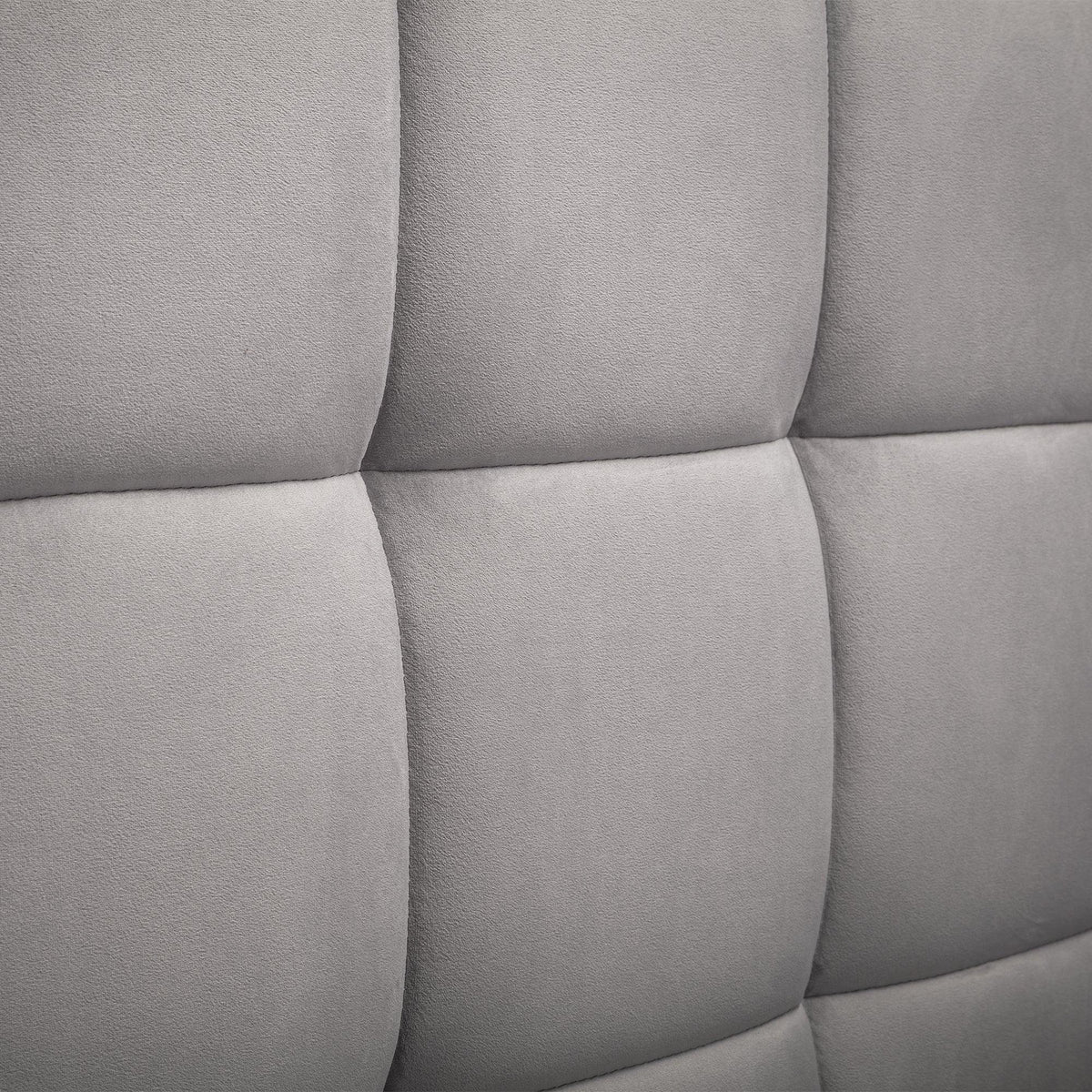 Close-up of grey fabric ottoman bed headboard with square stitched upholstery detail